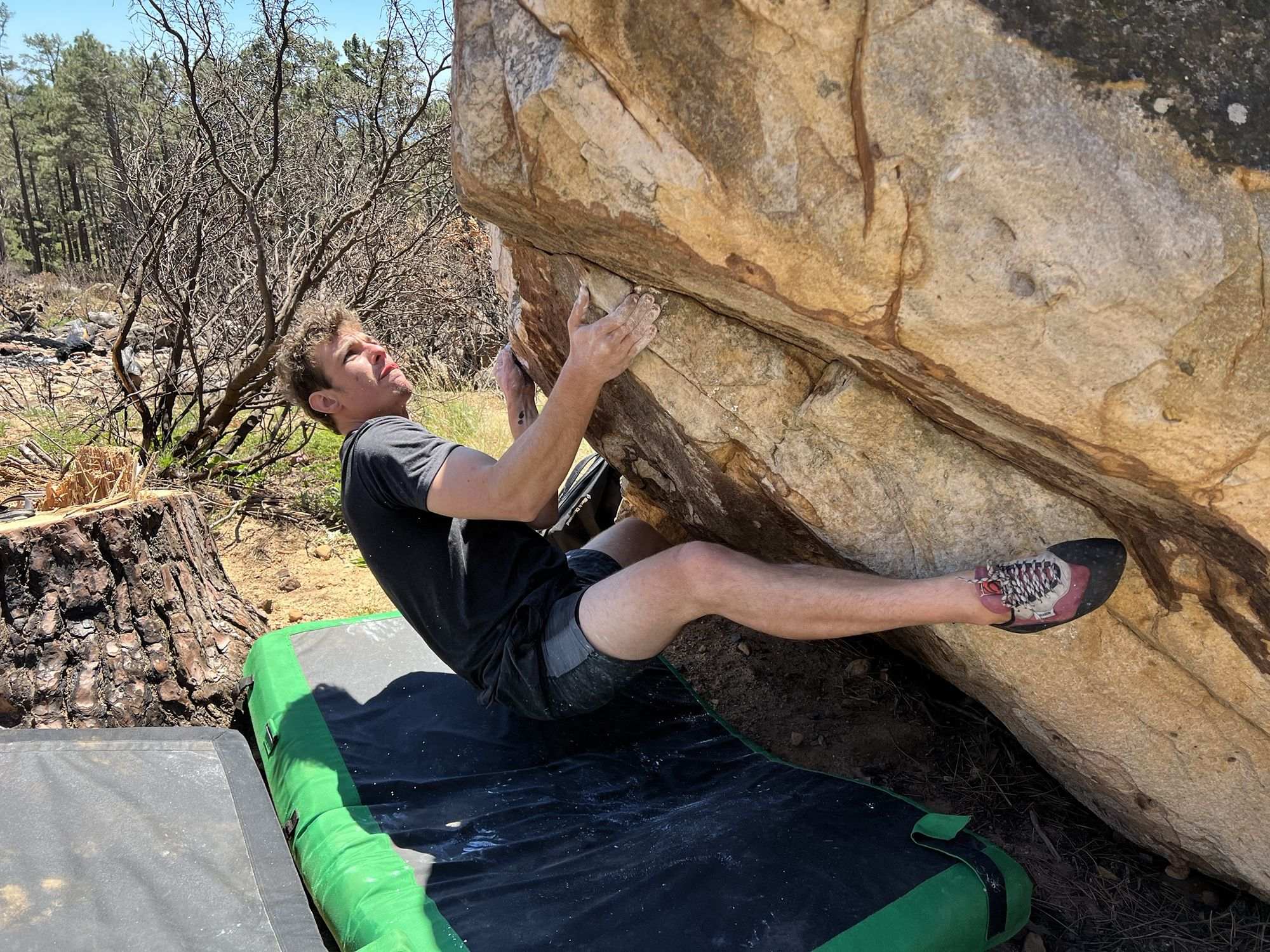 A climber working a bouldering problem outdoors